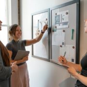 a group of women standing around a white board