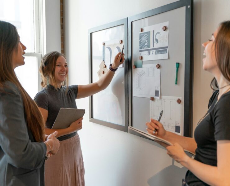 a group of women standing around a white board