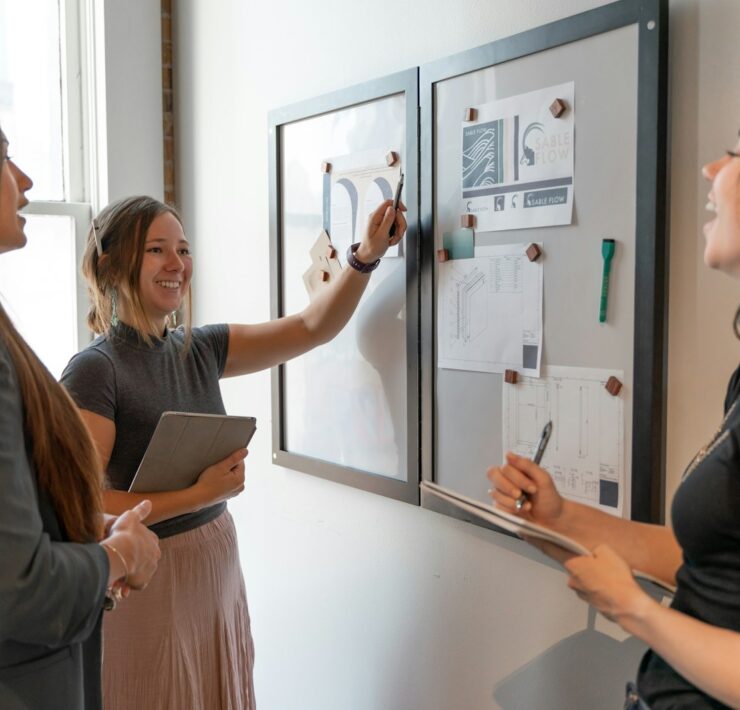 a group of women standing around a white board