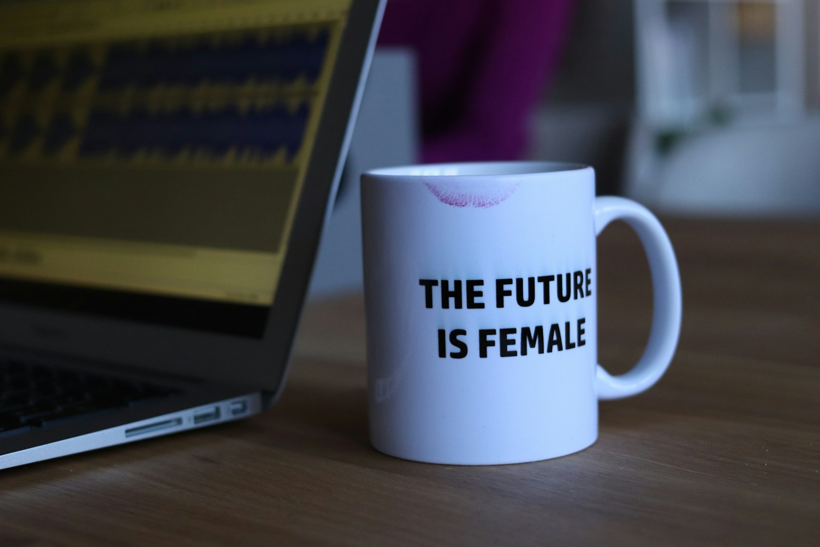 thefutureisfemale white and black printed ceramic mug beside laptop computer