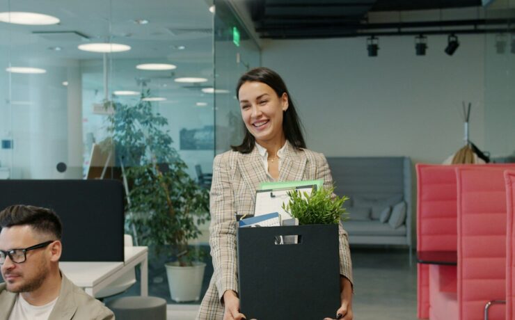 Woman carrying box of belongings leaving office