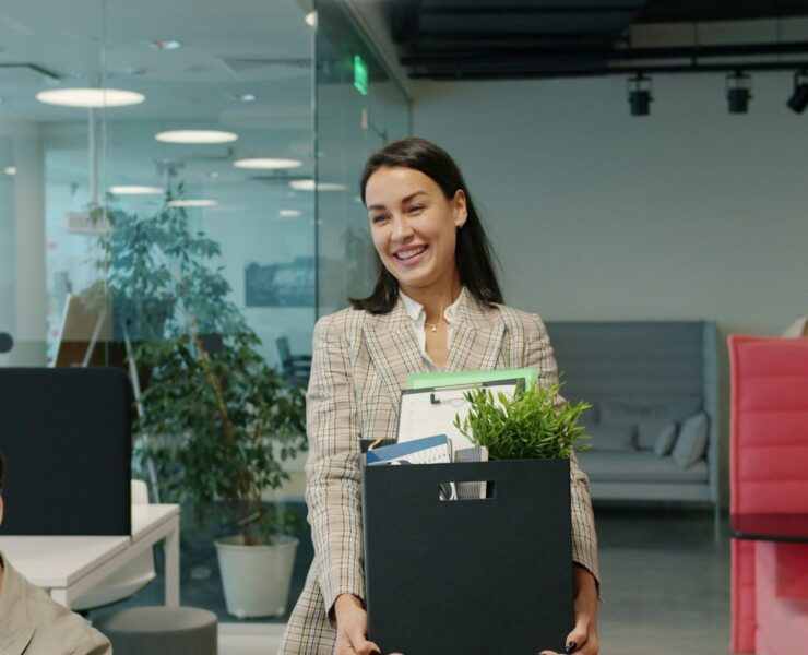 Woman carrying box of belongings leaving office