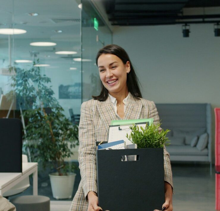 Woman carrying box of belongings leaving office